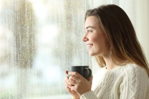 Coronavirus Covid 19 Updates - woman drinking tea looking out window during lockdown