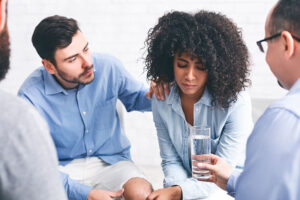 Peers consult woman and offer her water in a benzo addiction treatment center