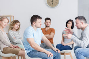 Man has intense conversation during group therapy while in ecstasy addiction treatment 