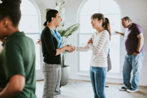 People shake hands and meet each other as they start an addiction alumni program