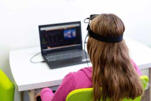 Woman sits at computer during neurofeedback program
