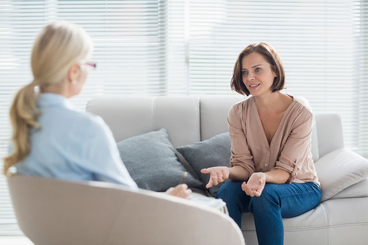 Women explaining something to a therapist with a clipboard taking notes