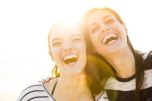 Two women smile on the beach