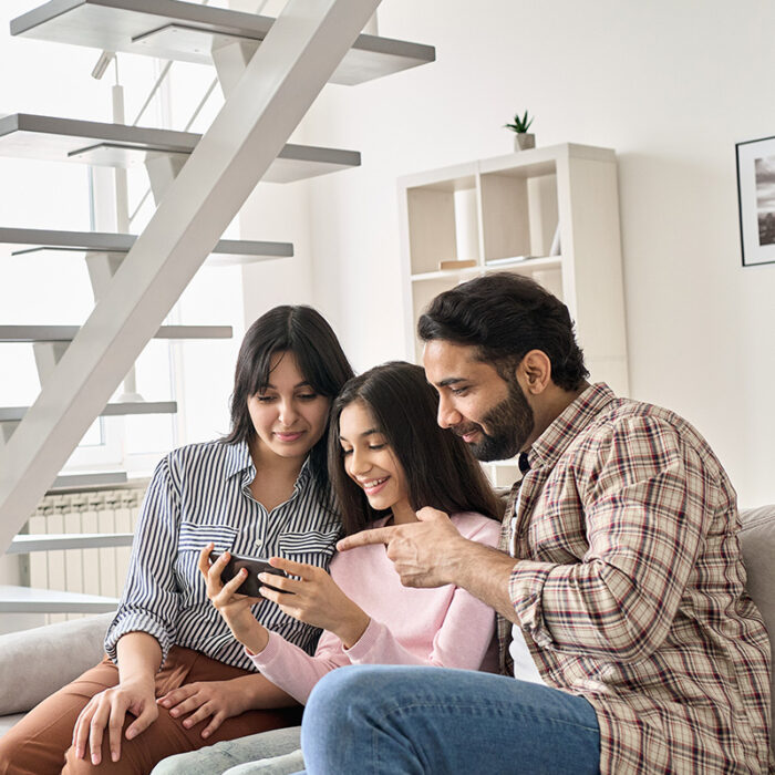 Family sit on couch and look at phone