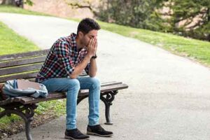 Man sits on bench as he tries to breathe and calm his anxiety