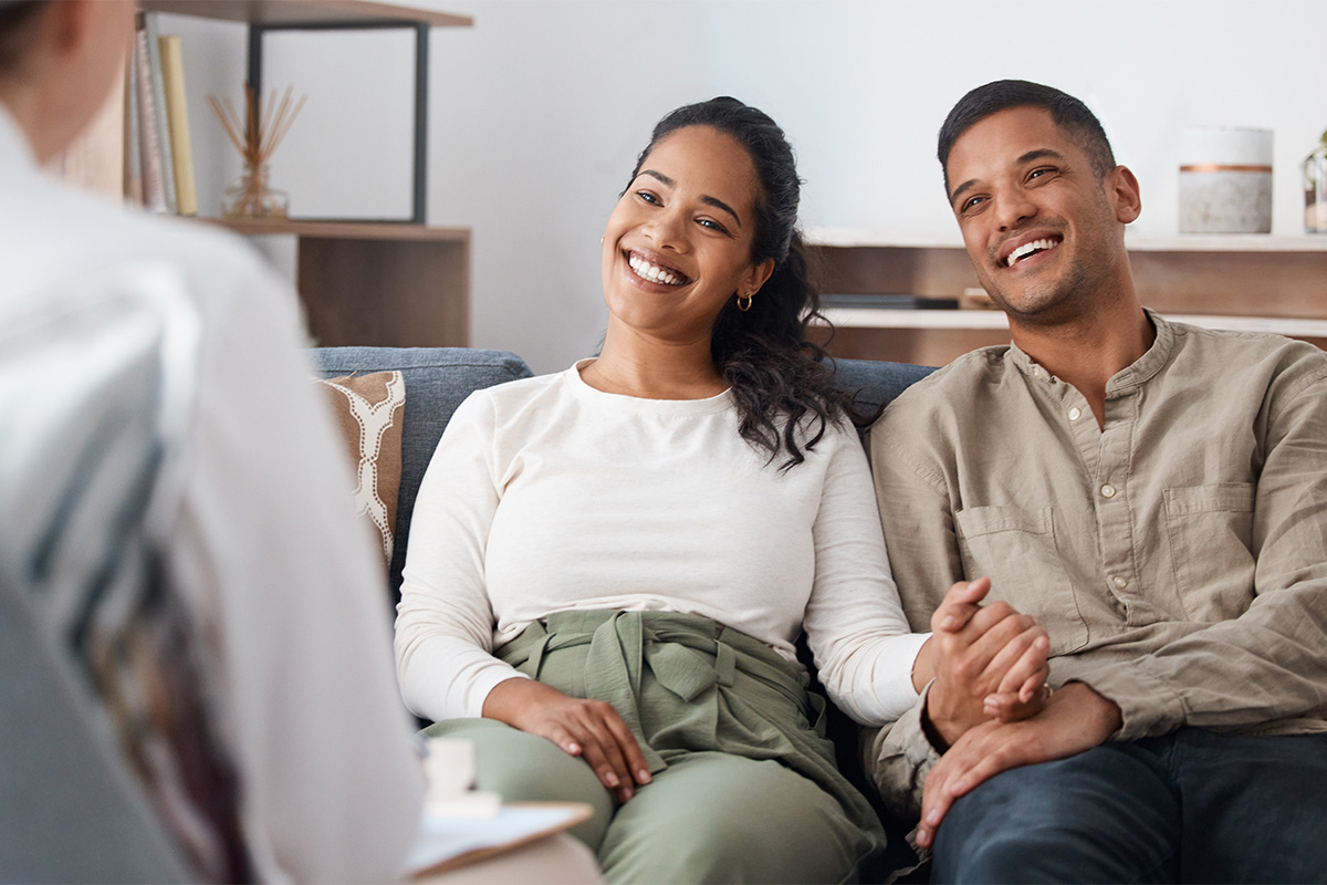 Couple hold hands as they talk to therapist in alcohol addiction treatment