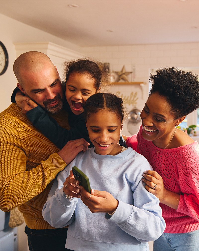 Family gathers around teen as she shows them pictures on phone