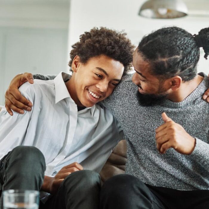 Man and son hold each other and laugh during mental health treatment