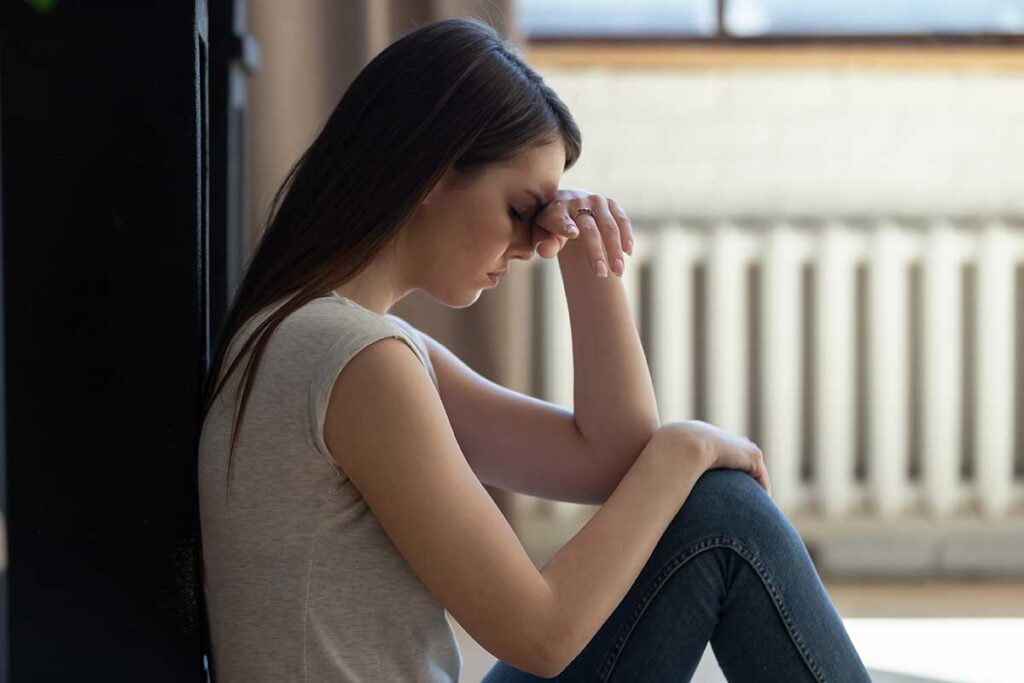 Teen girl sitting on the ground upset