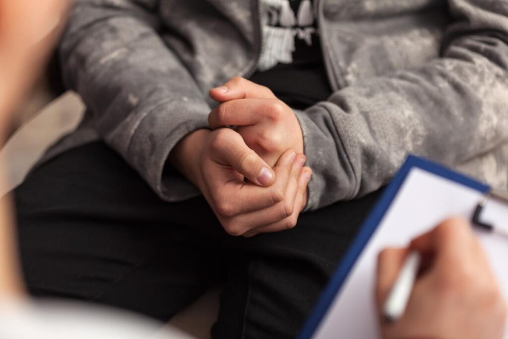 Nervous person talking to a therapist who is writing on a clipboard