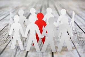 Paper figures surrounding a red figure to represent peer pressure