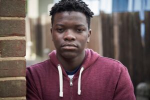 teen staring at the camera wearing a maroon hoodie