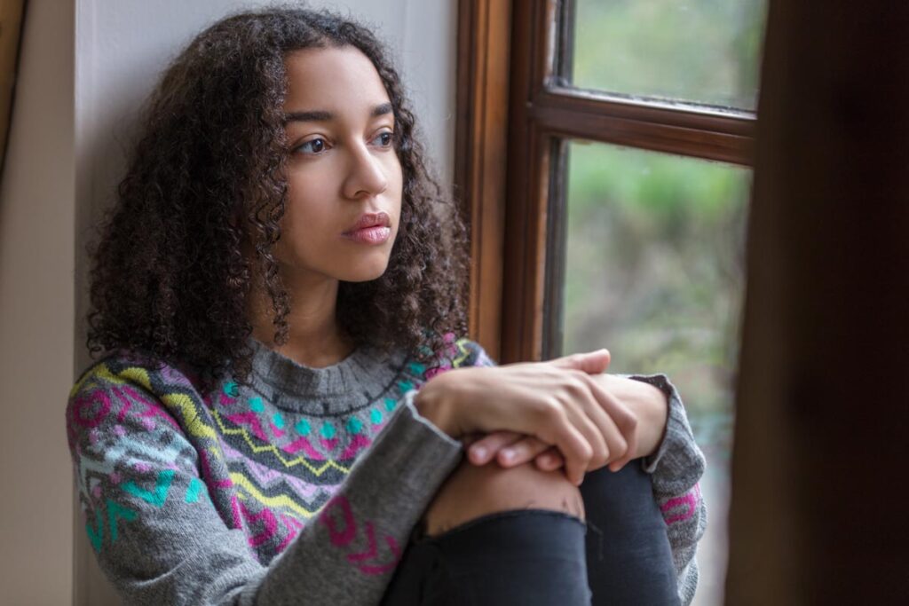 Teen girl sitting by a window thinking about mental health treatment in Boise, ID