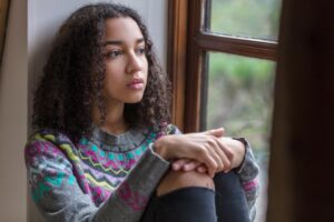 Teen girl sitting by a window thinking about mental health treatment in Boise, ID