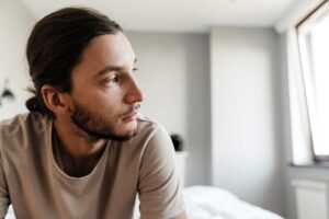 Man looks out window while pondering the long term side effects of Adderall