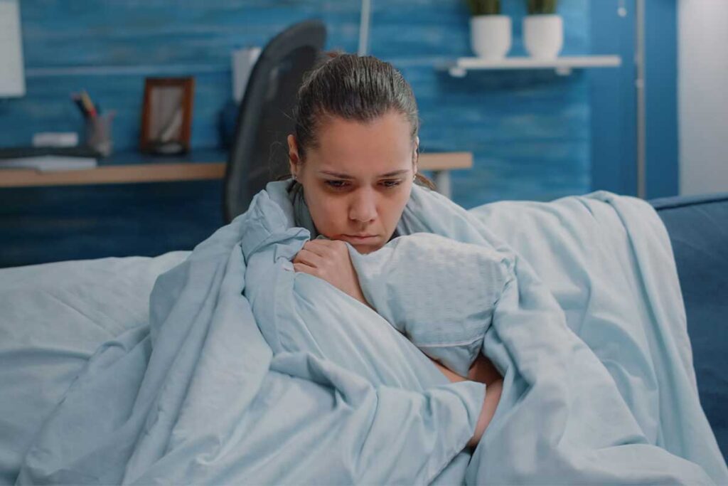 Woman in bed wrapped in a blanket thinking about signs of cocaine use