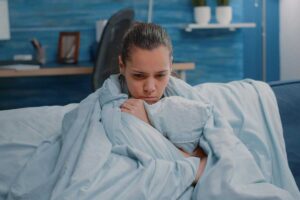 Woman in bed wrapped in a blanket thinking about signs of cocaine use