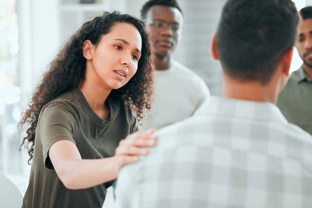 Women consoling a man in a group recovery session