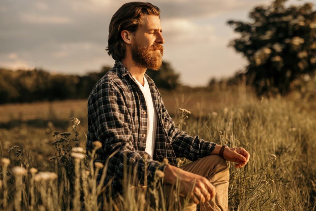 Man meditating in a field with sun shining