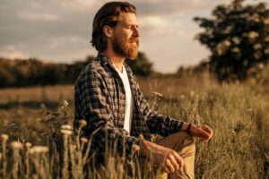 Man meditating in a field with sun shining