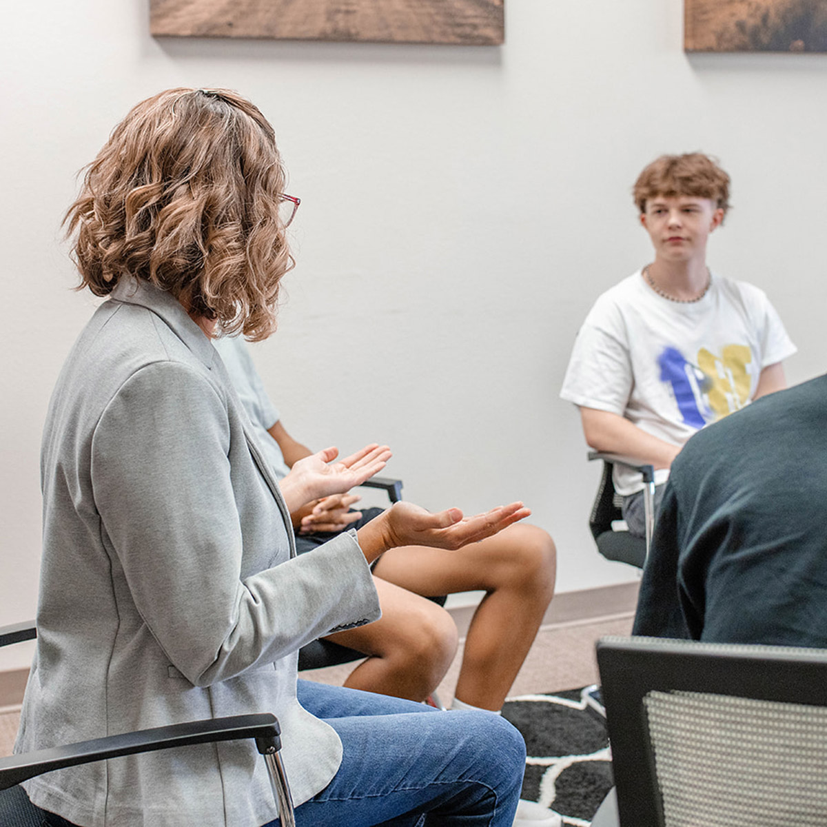 Adolescent boy listening to a therapist in a group session