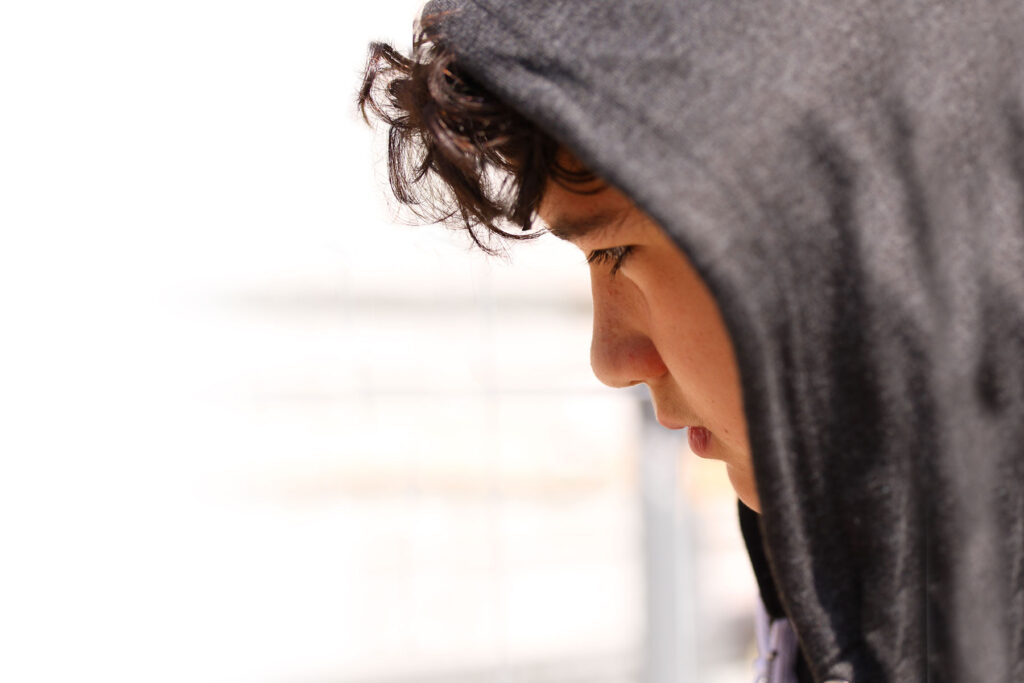 Teen in hoodie ponders his friends' behavior and wonders about substance abuse in teens