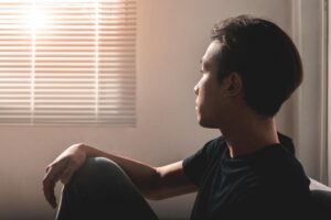 Man sits in dark and looks out window as he considers doing a THC detox