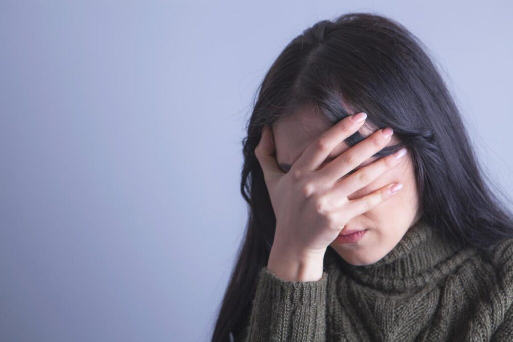 Woman puts head in hand as she struggles with wet brain
