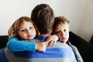 Man hugs his sons as he wonders if substance abuse affects relationships